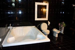 Persey Villa Borovets في بوروفتس: حمام ذو بلاط أسود مع حوض استحمام ومرحاض