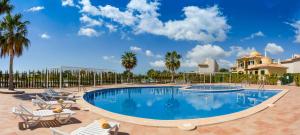 uma piscina num resort com cadeiras e palmeiras em Residence Club - Es Trenc Beach em Sa Ràpita