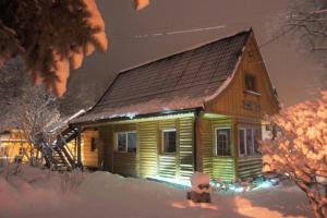 a wooden house with lights on it in the snow at Góralska Osada Karpacz - Apartametny in Karpacz