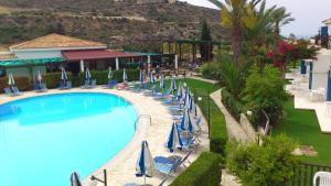 a pool at a resort with chairs and umbrellas at Hylatio Tourist Village in Pissouri