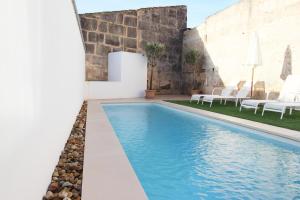 einen Pool in einem Garten mit Stühlen und einem Gebäude in der Unterkunft Sa Tanqueta in Ses Salines