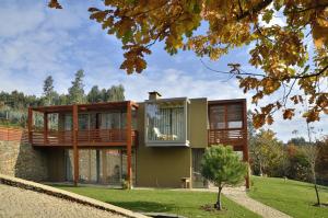 une maison avec un balcon et un arbre dans l'établissement Quinta da Longra, à Alvarenga