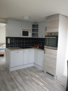 uma cozinha com armários brancos e electrodomésticos brancos em JaBaKi Child friendly home em Hoofddorp