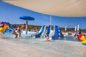 eine Gruppe von Menschen, die im Wasser an einem Pool spielen in der Unterkunft Eurocamp Mobile Homes at Campsite Lanterna in Poreč