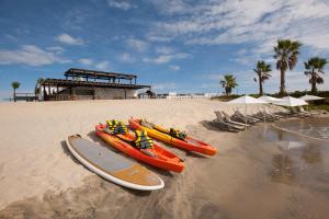 a group of kayaks on a beach with chairs and umbrellas at Hotel El Ganzo Adults Only in San José del Cabo