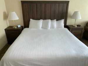 a bedroom with a large white bed with two lamps at Yellowstone Lodge in West Yellowstone
