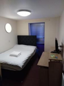 Cette petite chambre comprend un lit et un bureau avec une télévision. dans l'établissement Trigg Hall, à Bradford