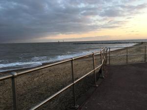 a beach with a metal fence and the ocean at Brookfield’s Apartment in Clacton-on-Sea