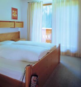 um quarto com uma cama grande e lençóis brancos em Ferienpension Senfter em Innervillgraten