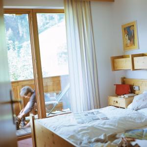 Un niño en un dormitorio con cama y ventana en Ferienpension Senfter, en Innervillgraten