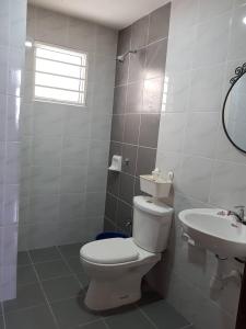 a white bathroom with a toilet and a sink at V’Auliya Residence in Putrajaya