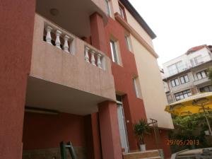 a red brick building with a window and a balcony at Kupenova Guest House in Sozopol