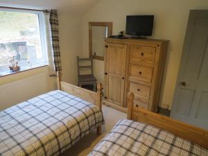 a bedroom with a bed and a dresser and a television at Yr Hen Farcdy in Talsarnau