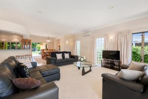 a living room with leather couches and a television at Lake View by Town in Taupo