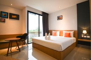 a hotel room with a bed and a table and a window at B Boutique Residence in Suratthani