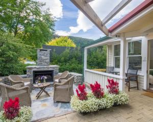 a patio with chairs and a stone fireplace at Arrowtown Lodge in Arrowtown