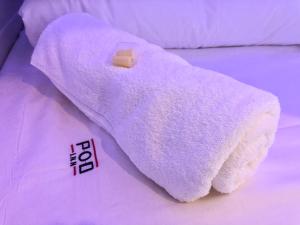 
a white towel laying on top of a white blanket at Pod Inn in Launceston
