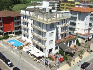 a large white building with a swimming pool next to a street at Hotel Rex in Lido di Savio