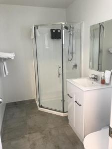 a white bathroom with a shower and a sink at Siesta Motel in Auckland