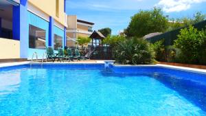a blue swimming pool with chairs and a house at Rentalmar Costa Verde in Cambrils