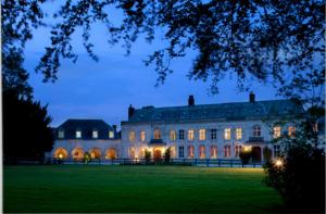 un grande edificio con le luci accese di notte di Château De Cocove a Recques-sur-Hem