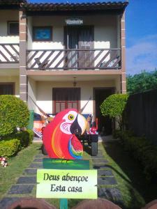 a sign in front of a house with a parrot statue at Casa em Praia Seca, Araruama. in Araruama