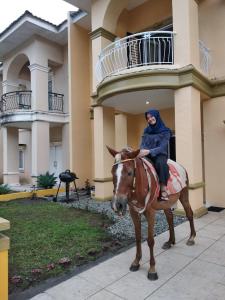 une femme faisant un cheval devant un bâtiment dans l'établissement Villa Brastagi Resort Jalan Mimpin Tua Blok C No. 41, à Berastagi