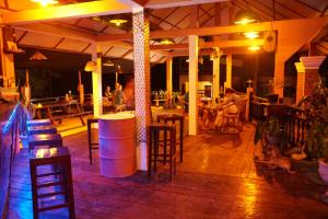 a restaurant with a bar and people sitting at tables at The Boathouse in Don Det