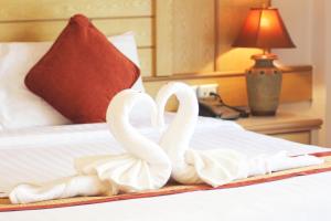 two white swans are sitting on a bed at Baan Boa Resort in Patong Beach