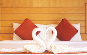two white swans standing on a bed with red pillows at Baan Boa Resort in Patong Beach