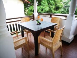 einen Tisch und Stühle auf einer Veranda mit einem Tisch in der Unterkunft Janu Homestay in Tangalle