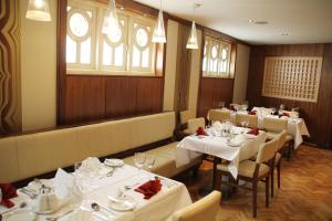 uma sala de jantar com mesas e cadeiras brancas e janelas em Hibernian Hotel & Leisure Centre em Mallow