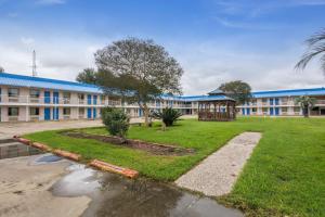 - un grand bâtiment avec une cour devant dans l'établissement Motel 6-Winnie, TX, à Winnie