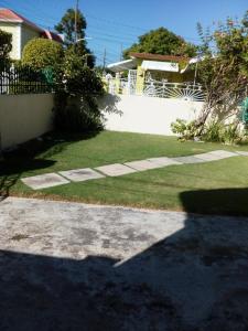 a yard with a white fence and grass at Cozy & Comfy in Portmore