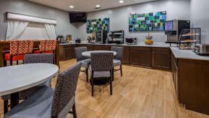 a kitchen with two tables and chairs and a counter at Best Western Clubhouse Inn & Suites in Mineral Wells