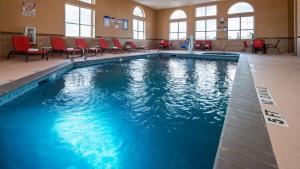 a large swimming pool with red chairs in a building at Best Western Plus Lubbock Windsor Inn in Lubbock