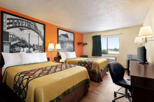 ein Hotelzimmer mit 2 Betten und einem Stuhl in der Unterkunft Super 8 by Wyndham Waco University Area in Waco