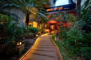 une passerelle devant un bâtiment planté de palmiers dans l'établissement Goldfinch Hotel Bangalore, à Bangalore