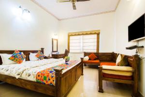 Hotel Raj Kothi Jaipur airport في جايبور: غرفة نوم بسريرين وتلفزيون وأريكة