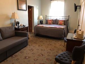 a bedroom with a bed and a couch and a chair at Hotel Sutter in Sutter Creek