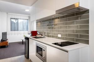 a kitchen with a stove top oven and a microwave at Ramada by Wyndham VetroBlu Scarborough Beach in Perth