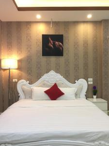 a bedroom with a white bed with a red pillow at HD Hotel Nội Bài in Noi Bai