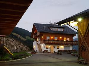 una casa en las montañas con sus luces encendidas en Ferienwohnungen Kuentnerhof en San Candido