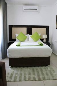 a bedroom with a large bed with green pillows at Overflow Guest House in Gaborone