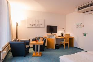 Zimmer mit Stühlen, einem Schreibtisch und einem TV in der Unterkunft Hotel Alte Werft in Papenburg