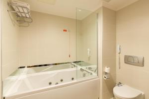 a bathroom with a tub and a toilet and a phone at Kefaluka Resort in Akyarlar