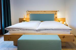 a bedroom with a bed with a wooden headboard and a blue bench at Hotel Feldrand in Riobianco