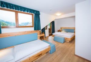 a room with two beds and two windows at Hotel Feldrand in Riobianco