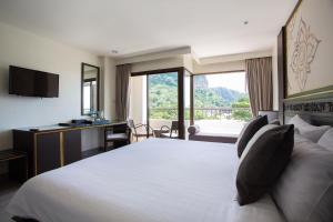 a hotel room with a bed and a desk and a window at Krabi Heritage Hotel in Ao Nang Beach