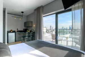 een slaapkamer met een bed en een keuken met een groot raam bij The Roof - By Sea Land Suites in Tel Aviv